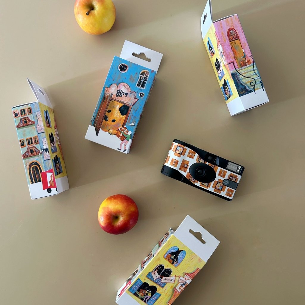 Small camera and its packaging on a beige surface with apples.